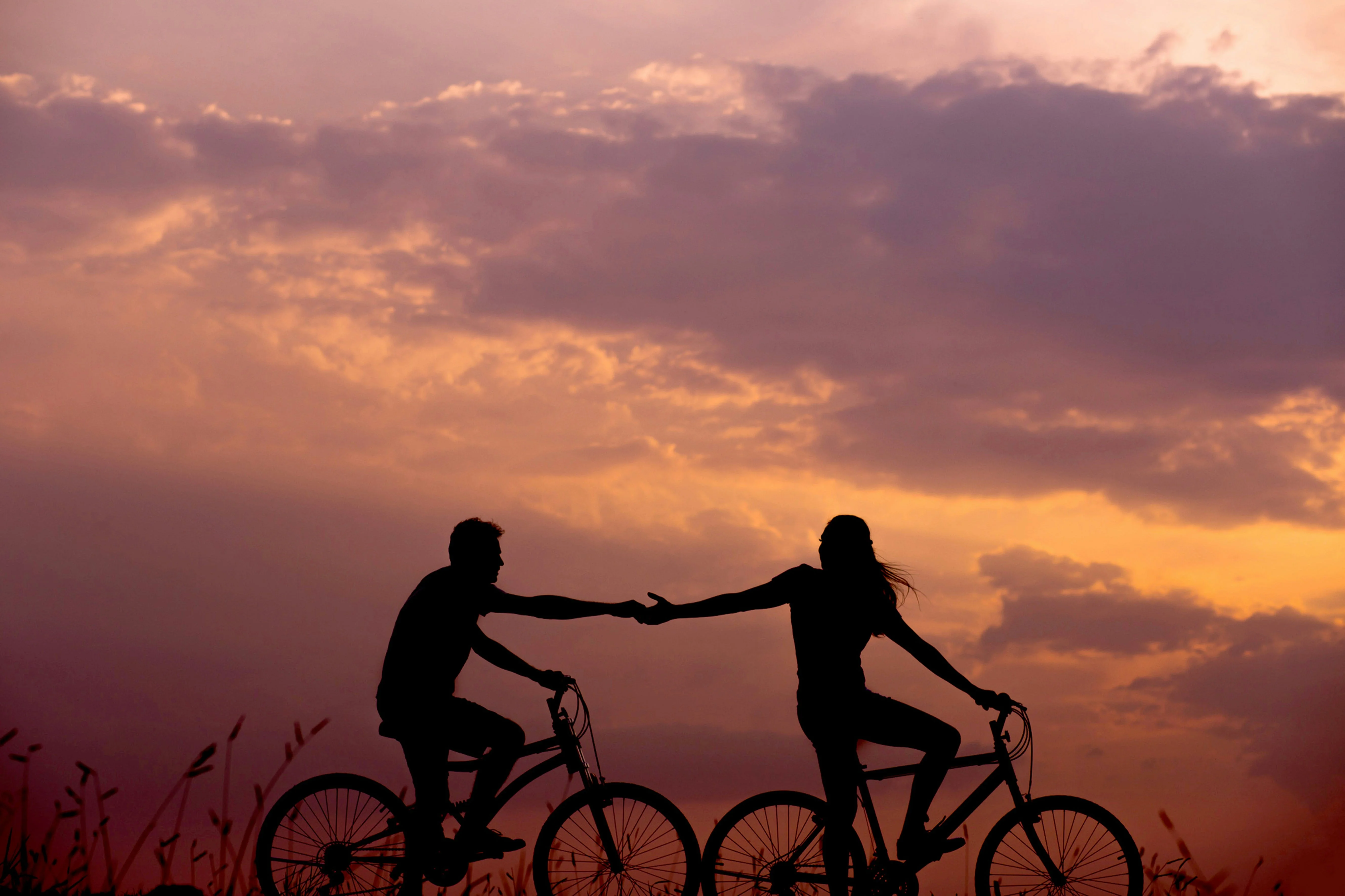 two people holding hands while biking 