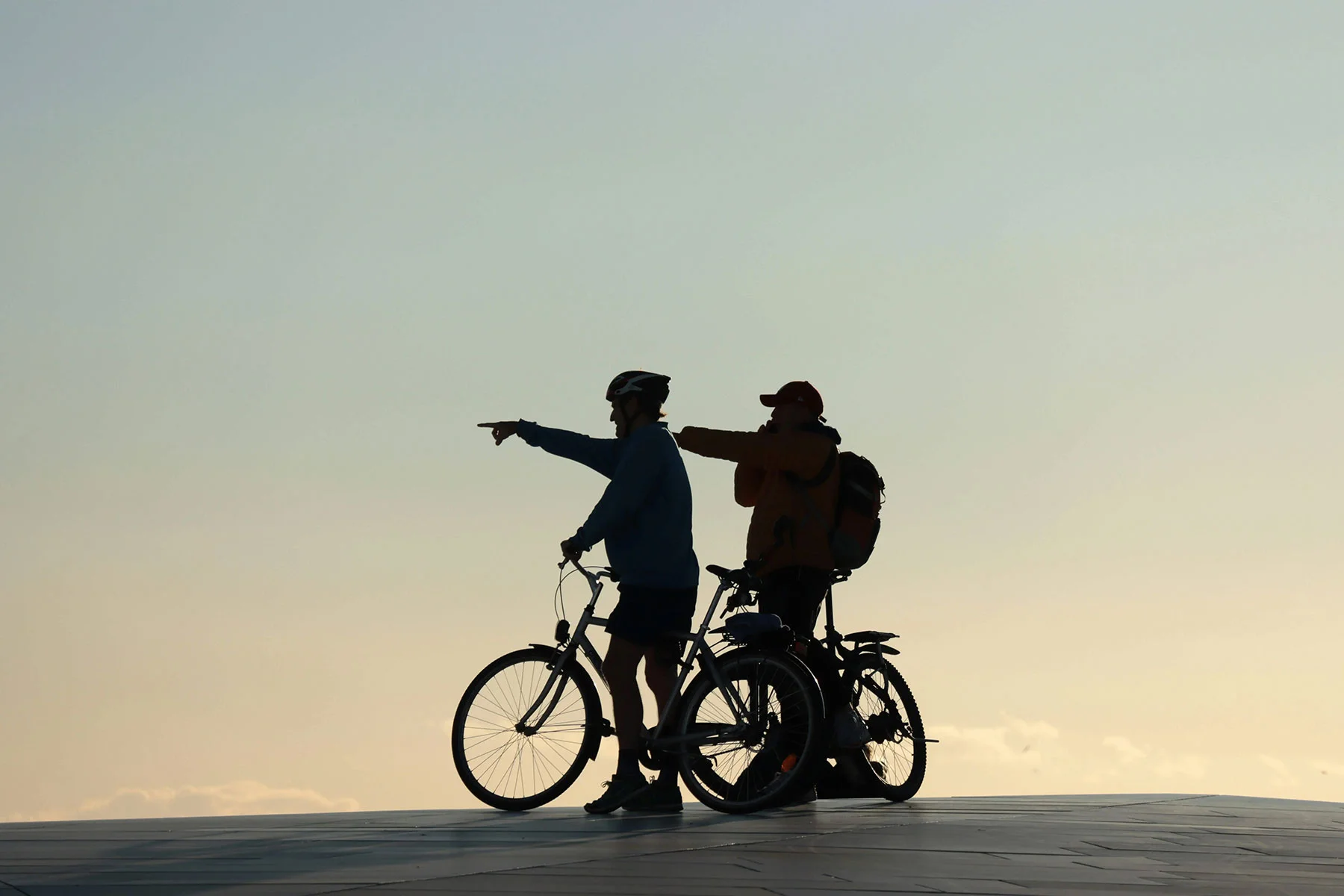 two people biking and pointing during sunset